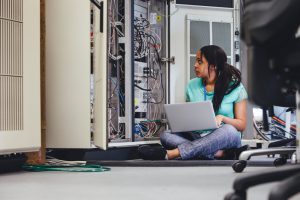 Female student checking on network servers using a laptop.